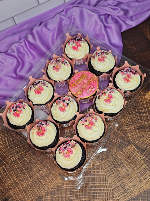 Chocolate cupcakes with white buttercream and pink decorations.