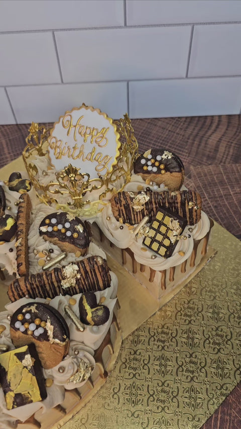 Panning video of custom buttercream number cake, decorated with biscoff cookies, mini chocolate bars, gold sprinkles and biscoff drip.