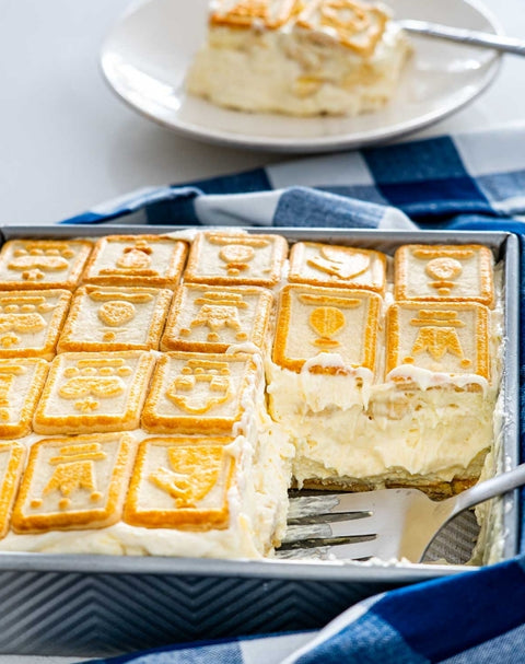 Close up of banana pudding, topped with chessman cookies being serving with a spatula. 