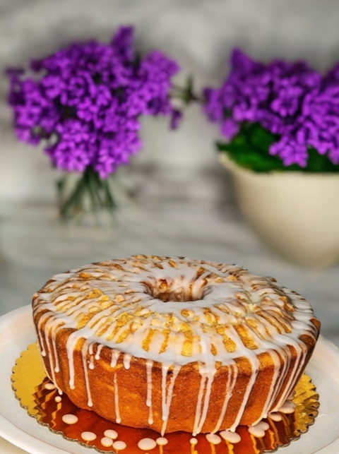 Lemon Drizzle Pound Cake with purple flowers in the background.