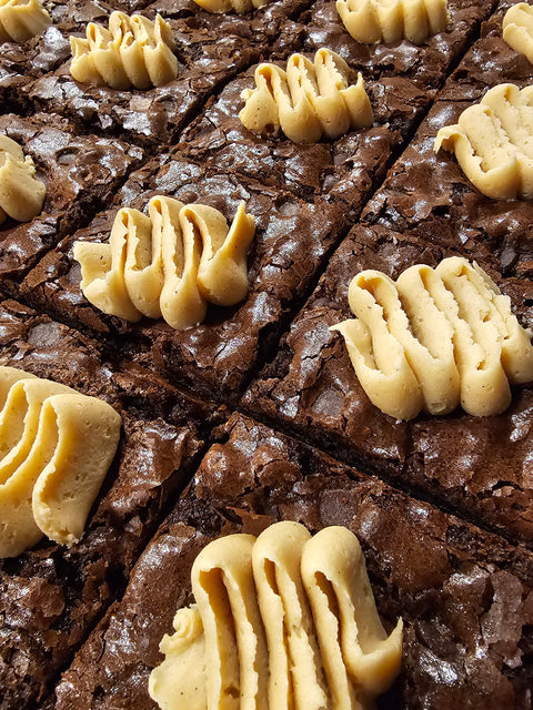 Close up of sliced fudge brownies with crackly skin and peanut butter buttercream on top