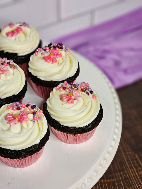 Close up of the chocolate cupcakes with pink decorations and white buttercream.